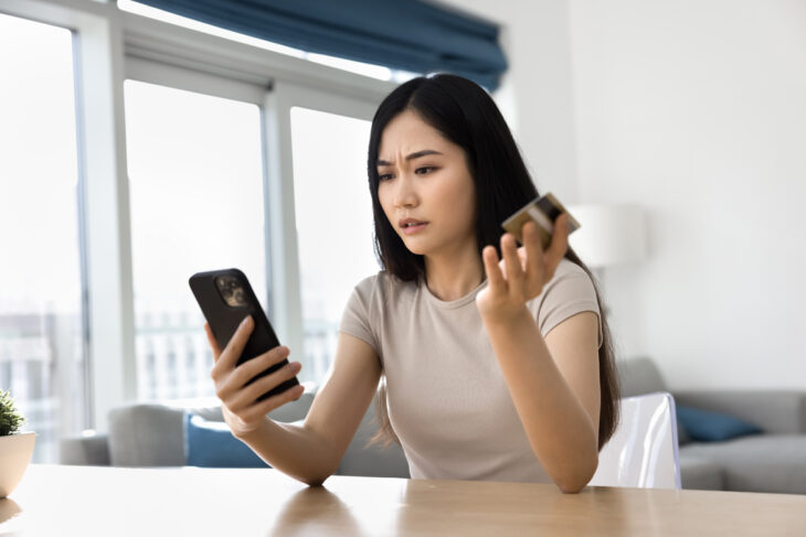 person holding their credit card looking at their phone