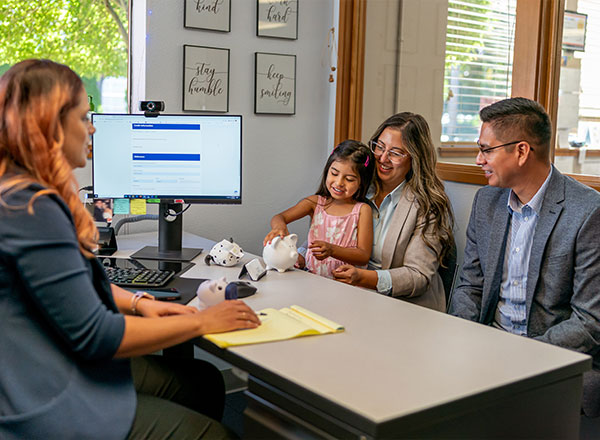 Padres con hija en el banco abriendo una cuenta juvenil