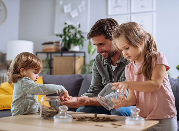 Papá con hijo e hija recogiendo el dinero que han ahorrado