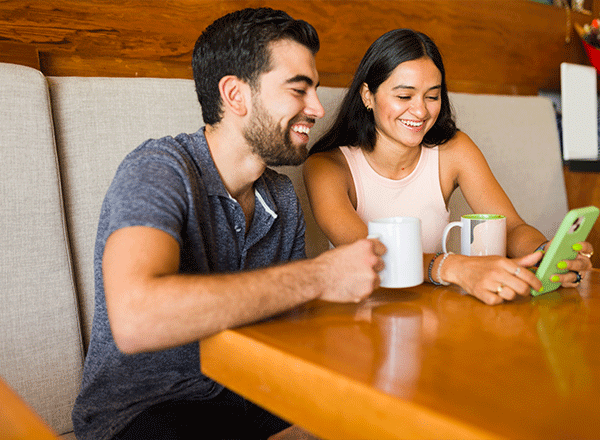 Smiling couple using a laptop, representing the convenience and benefits of managing a Basic Checking Account online.